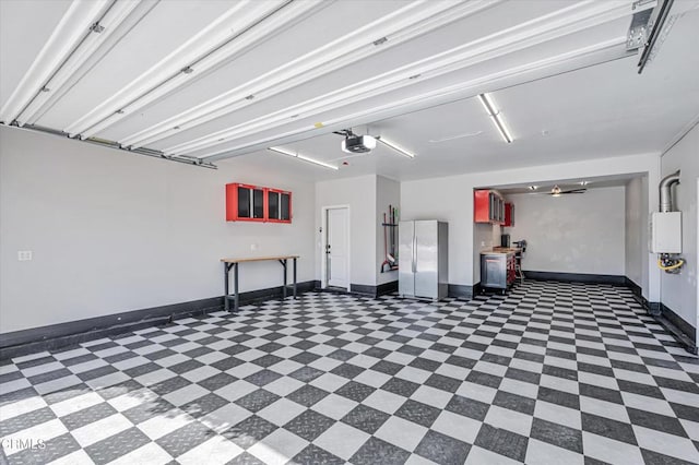 garage featuring baseboards, freestanding refrigerator, and a garage door opener