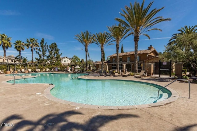 community pool with a patio area and fence