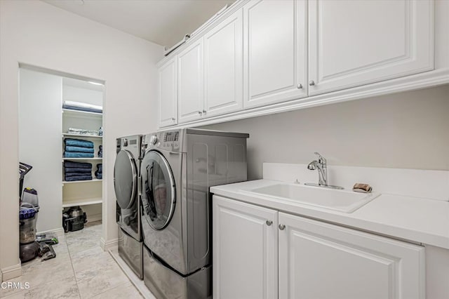 laundry area with a sink, washing machine and clothes dryer, and cabinet space