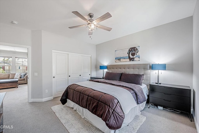 bedroom with a closet, light colored carpet, baseboards, and a ceiling fan