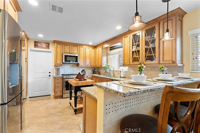 5303 Avondale Way, Riverside, CA 92506 - kitchen with visible vents, a peninsula, a breakfast bar, appliances with stainless steel finishes, and backsplash