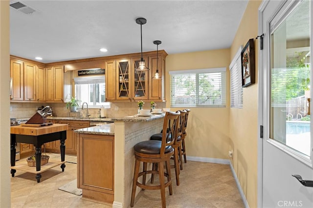 5303 Avondale Way, Riverside, CA 92506 - kitchen featuring backsplash, a peninsula, a breakfast bar, and glass insert cabinets