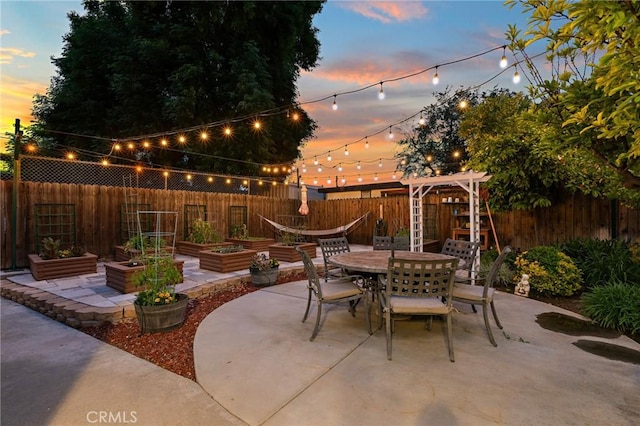 5303 Avondale Way, Riverside, CA 92506 - patio terrace at dusk featuring a fenced backyard, a vegetable garden, and outdoor dining space