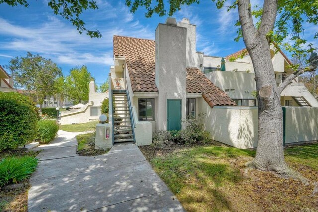 321 N Melrose Dr Unit A, Vista, CA 92083 - townhome / multi-family property featuring stucco siding, a chimney, stairway, a tiled roof, and fence