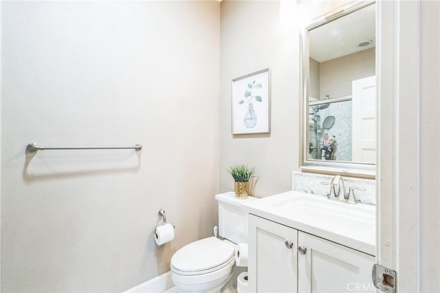 bathroom with a shower with shower door, vanity, baseboards, and toilet
