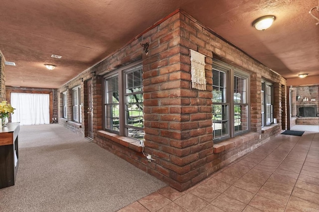2483 Buckman Springs Rd, Campo, CA 91906 - hallway with plenty of natural light, tile patterned flooring, a textured ceiling, brick wall, and carpet