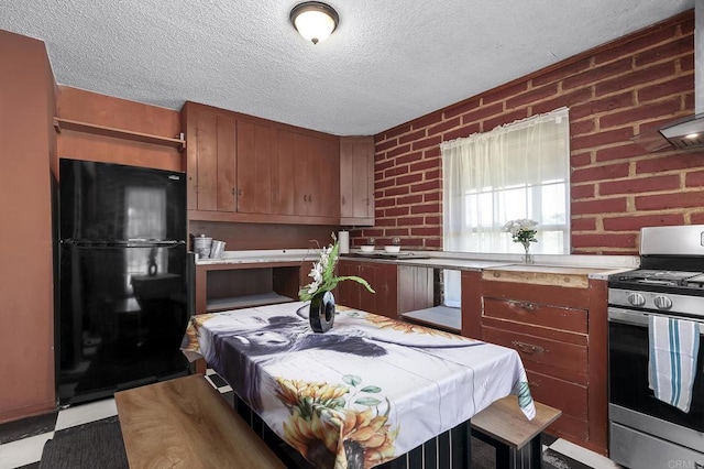 2483 Buckman Springs Rd, Campo, CA 91906 - kitchen with gas range, freestanding refrigerator, brick wall, a textured ceiling, and brown cabinetry