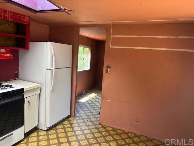 2483 Buckman Springs Rd, Campo, CA 91906 - kitchen with range with gas stovetop, freestanding refrigerator, light countertops, light floors, and ventilation hood