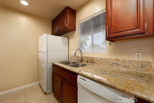 kitchen with baseboards, recessed lighting, white appliances, light tile patterned floors, and a sink