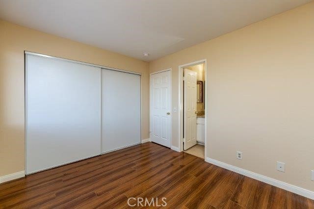 unfurnished bedroom with baseboards, connected bathroom, and wood finished floors