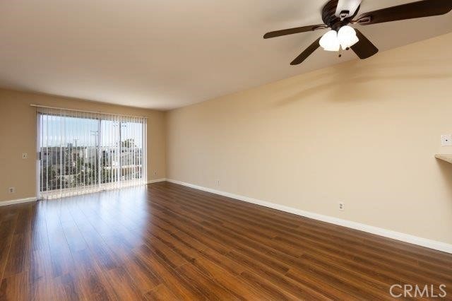 spare room with dark wood-style flooring, baseboards, and ceiling fan