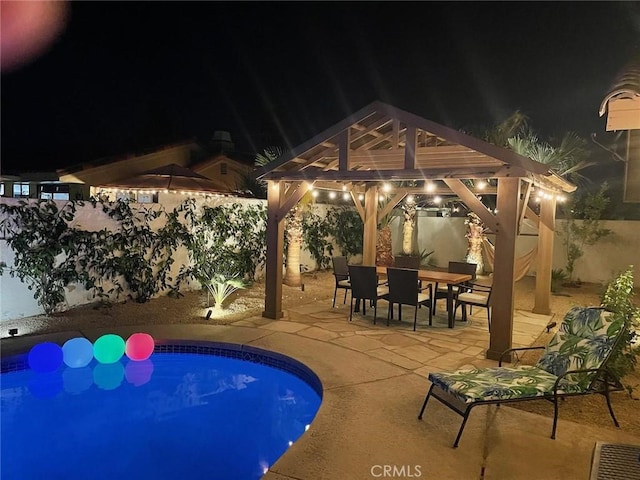 43590 Warner Trl, Palm Desert, CA 92211 - pool at night with outdoor dining space, a gazebo, a fenced backyard, a fenced in pool, and a patio area