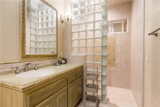 full bathroom with tiled shower and vanity