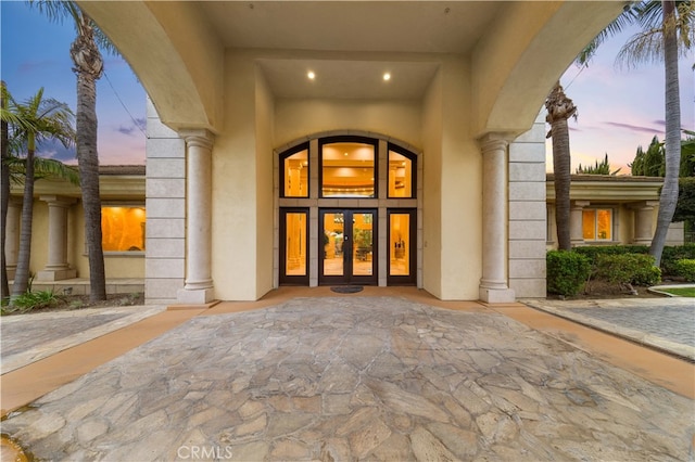 exterior entry at dusk with french doors and stucco siding
