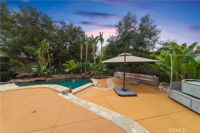 pool at dusk featuring a fenced backyard, a patio, an outdoor hangout area, and a pool