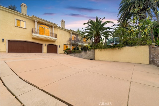 1199 Village Dr, Chino Hills, CA 91709 - view of front of house featuring an attached garage, driveway, a balcony, a chimney, and stucco siding