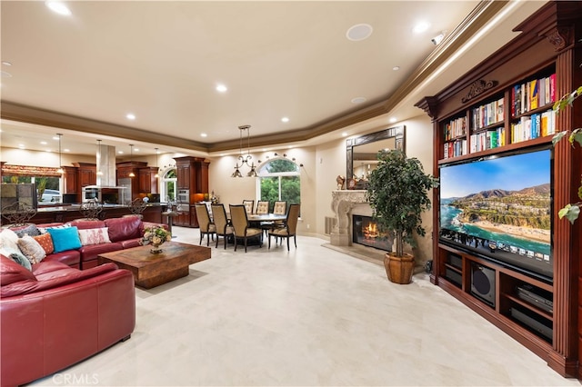 living area with ornamental molding, a tray ceiling, and a high end fireplace