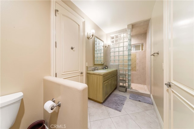 bathroom featuring toilet, tiled shower, tile patterned flooring, and vanity