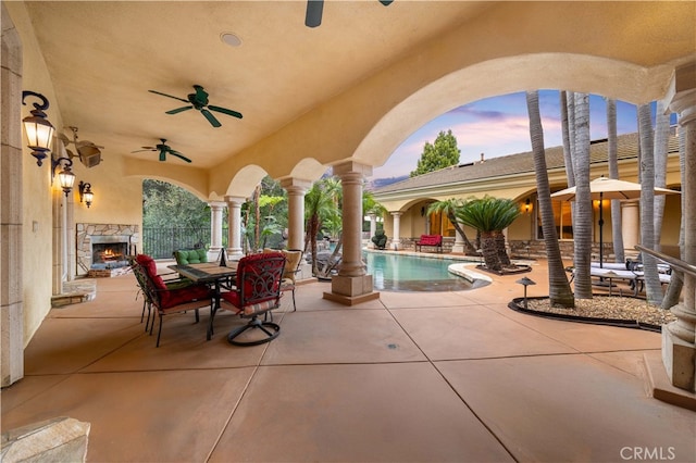 view of patio with an outdoor pool, ceiling fan, and an outdoor stone fireplace