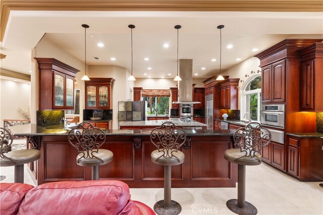 kitchen with tasteful backsplash, a breakfast bar, dark stone counters, appliances with stainless steel finishes, and island range hood