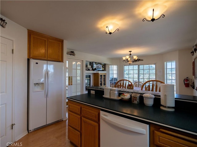 406 Delle Dr, Crestline, CA 92325 - kitchen featuring dark countertops, white appliances, a chandelier, brown cabinetry, and light wood-style flooring