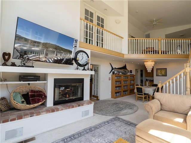 406 Delle Dr, Crestline, CA 92325 - living area with a fireplace, a ceiling fan, stairway, a high ceiling, and carpet flooring