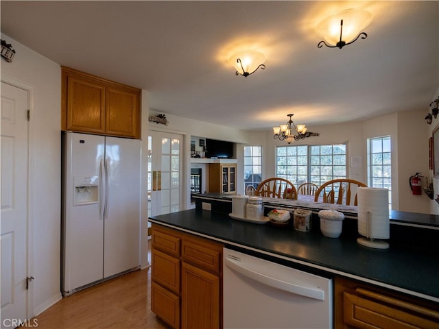 406 Delle Dr, Crestline, CA 92325 - kitchen featuring a chandelier, white appliances, dark countertops, light wood-style floors, and brown cabinetry