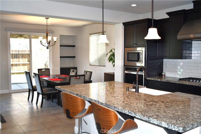 1019 El Molino Ave, Clovis, CA 93619 - kitchen featuring tasteful backsplash, an inviting chandelier, a wealth of natural light, wall chimney exhaust hood, and appliances with stainless steel finishes