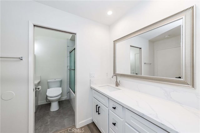 full bath with combined bath / shower with glass door, vanity, baseboards, and toilet