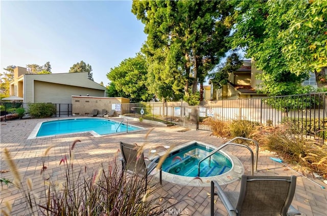 pool with fence, a patio, and a hot tub