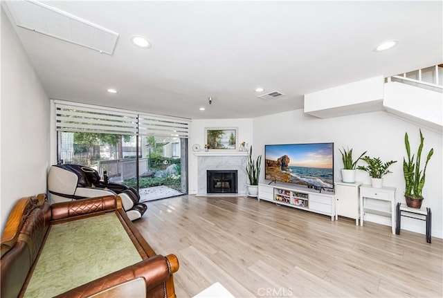 living room featuring visible vents, light wood-style flooring, recessed lighting, and a high end fireplace
