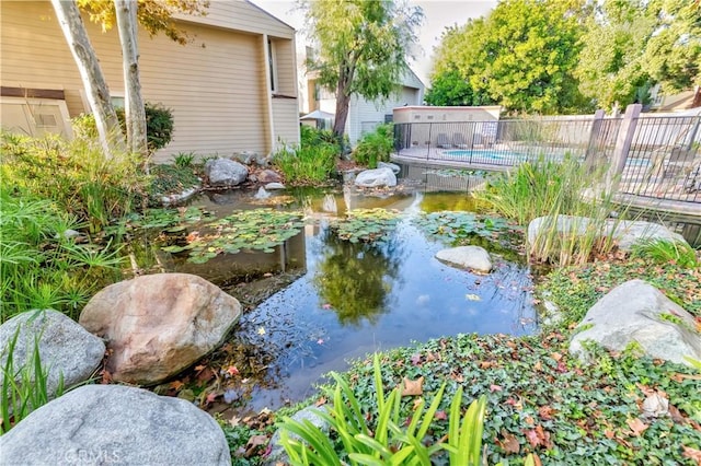 view of yard with a fenced in pool, a small pond, and fence