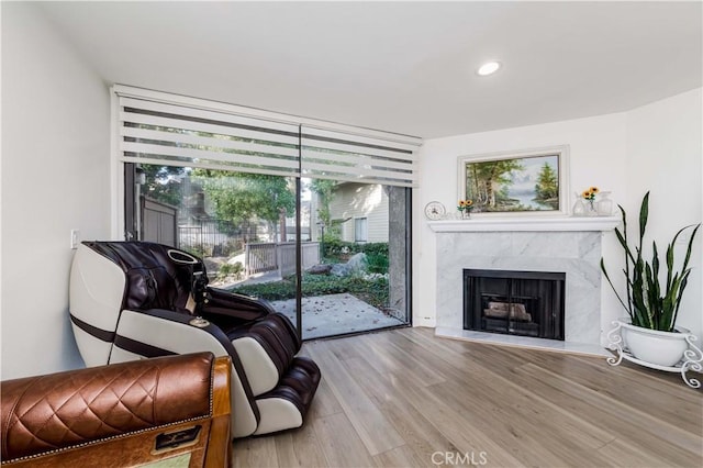 sitting room featuring a premium fireplace, wood finished floors, floor to ceiling windows, and recessed lighting