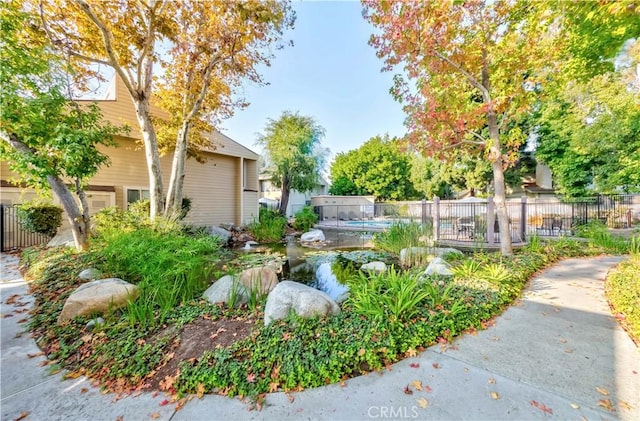 view of yard with a garden pond, a fenced in pool, and fence