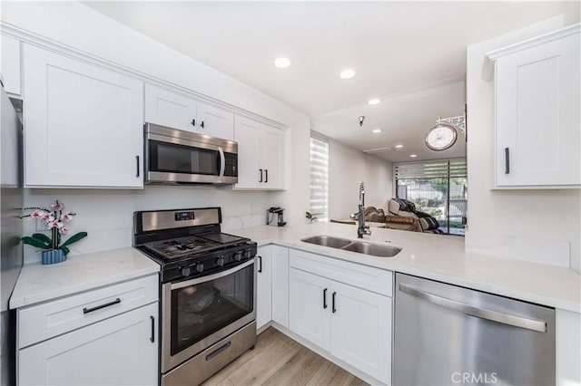 kitchen with light wood-style floors, white cabinetry, recessed lighting, appliances with stainless steel finishes, and a sink