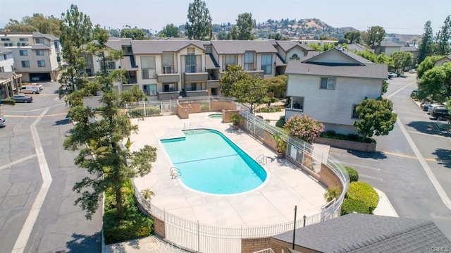 community pool featuring a patio, fence, and a residential view