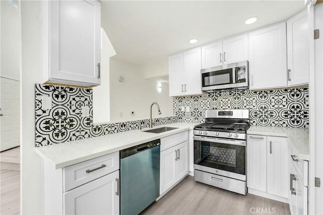kitchen featuring a sink, light countertops, white cabinets, light wood finished floors, and stainless steel appliances