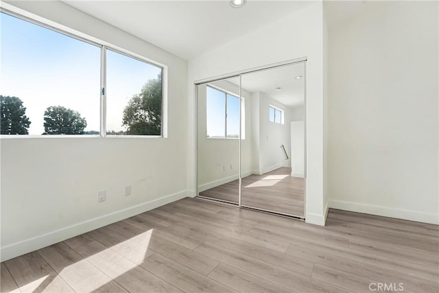 unfurnished bedroom with baseboards, a closet, recessed lighting, and wood finished floors