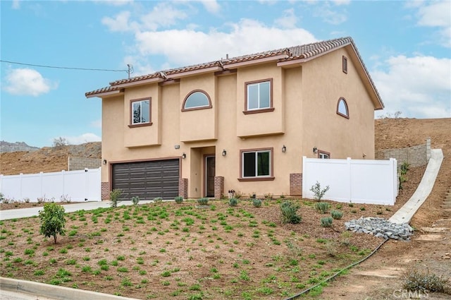 view of front of house with an attached garage, stucco siding, and fence