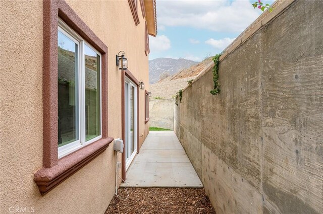 view of side of home featuring a patio, a mountain view, stucco siding, and fence