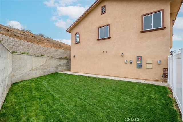 back of property with a yard, stucco siding, and a fenced backyard