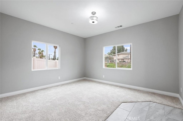 unfurnished room with light carpet, visible vents, baseboards, and a healthy amount of sunlight