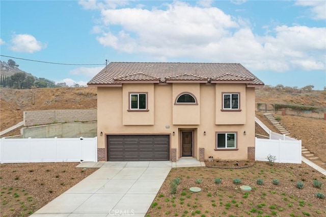 mediterranean / spanish-style home with concrete driveway, stucco siding, fence, and a garage