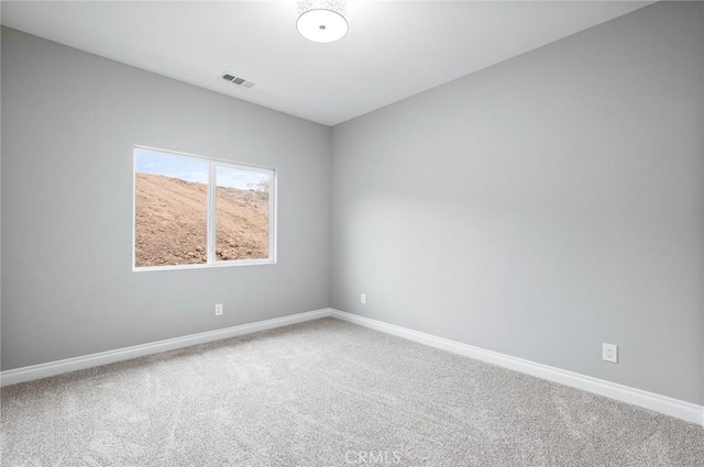 carpeted spare room with visible vents and baseboards