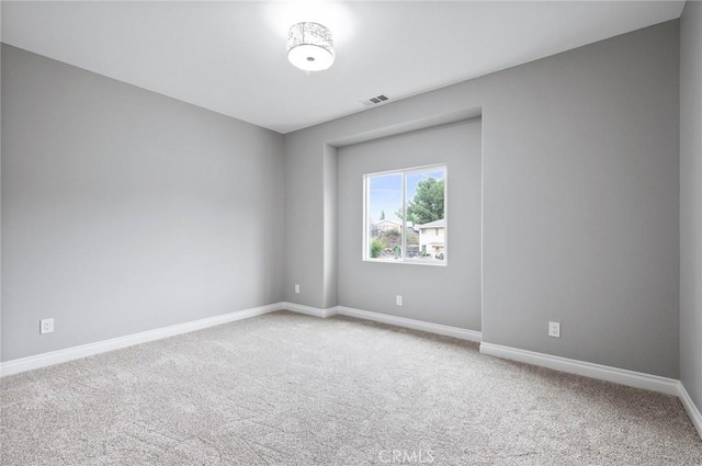 carpeted spare room featuring baseboards and visible vents