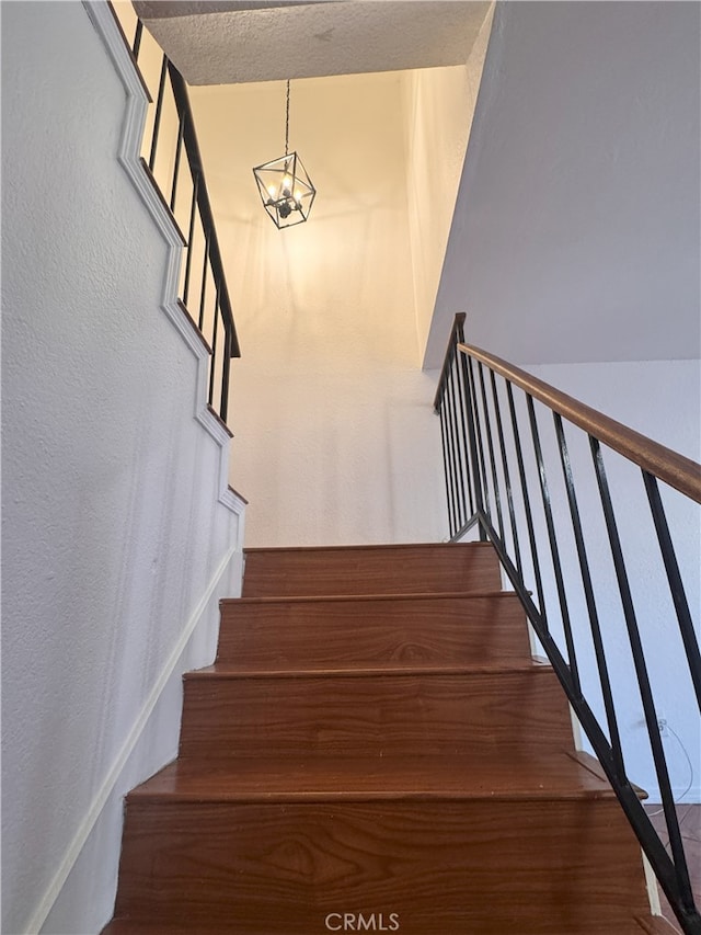9208 Citrus Ave Unit C, Fontana, CA 92335 - stairway featuring a textured wall, wood finished floors, and an inviting chandelier