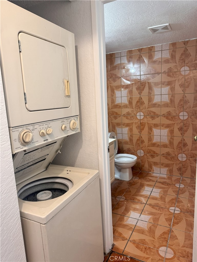 9208 Citrus Ave Unit C, Fontana, CA 92335 - laundry area featuring a textured ceiling, light tile patterned floors, laundry area, stacked washer and dryer, and visible vents