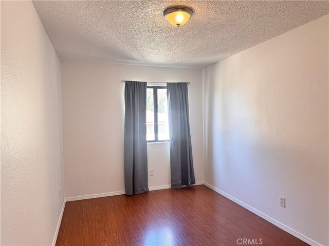 9208 Citrus Ave Unit C, Fontana, CA 92335 - spare room featuring baseboards, dark wood-type flooring, and a textured ceiling