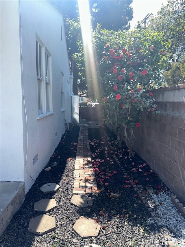 view of side of property with stucco siding and fence