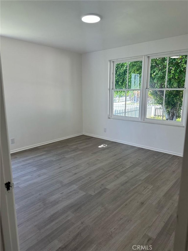 empty room with baseboards and dark wood-style floors